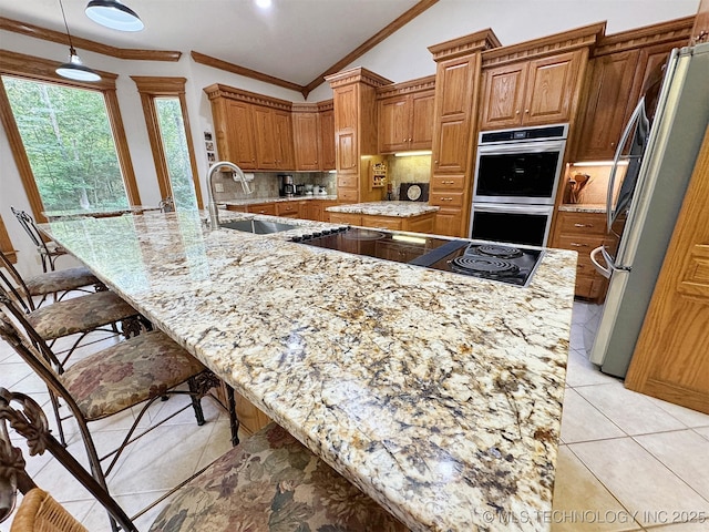 kitchen with lofted ceiling, sink, stainless steel appliances, and light stone countertops