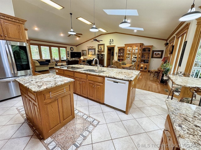 kitchen with pendant lighting, sink, stainless steel fridge, white dishwasher, and a center island with sink