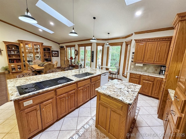 kitchen with lofted ceiling with skylight, sink, pendant lighting, black electric stovetop, and a kitchen island with sink