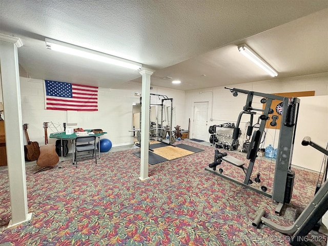 workout area featuring carpet floors, decorative columns, and a textured ceiling