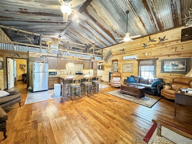 living room featuring ceiling fan, high vaulted ceiling, light hardwood / wood-style flooring, and an AC wall unit