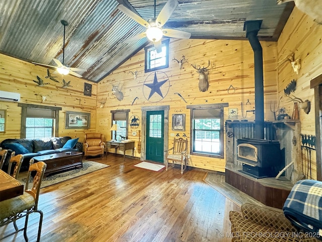 living room featuring wood-type flooring, wooden ceiling, ceiling fan, and a wood stove