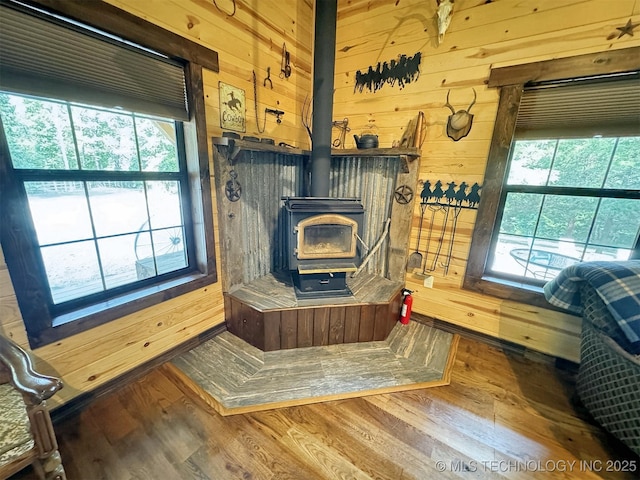 interior space with wood-type flooring, wooden walls, and a wood stove