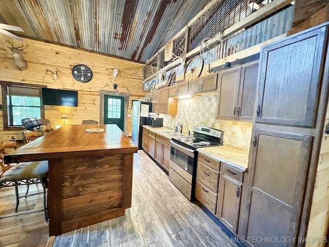 kitchen featuring appliances with stainless steel finishes, wooden walls, light hardwood / wood-style floors, and plenty of natural light