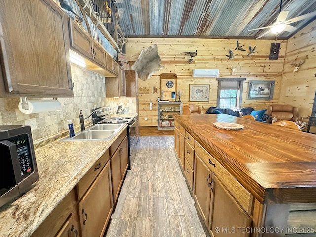 kitchen featuring light hardwood / wood-style flooring, a wall mounted AC, butcher block countertops, and wood walls