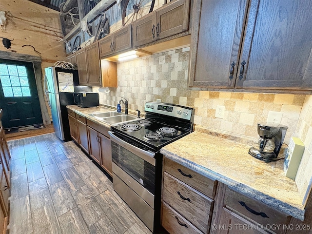 kitchen with light stone counters, sink, decorative backsplash, and stainless steel appliances