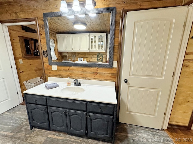 bathroom with wooden ceiling, wood-type flooring, vanity, and wood walls