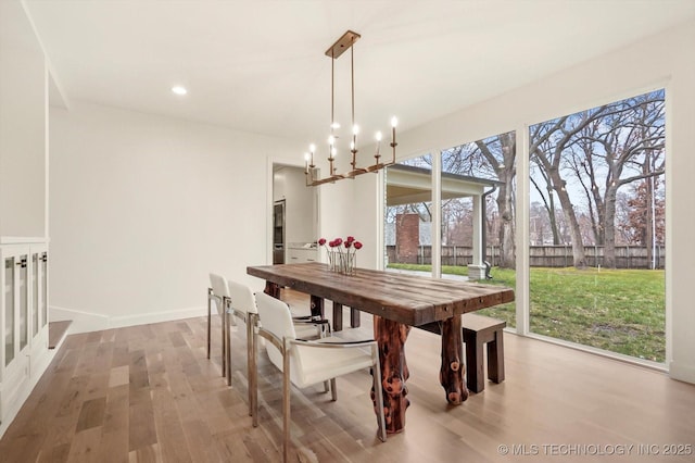 dining space with light hardwood / wood-style floors and a chandelier