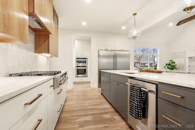 kitchen featuring white cabinetry, pendant lighting, stainless steel appliances, light hardwood / wood-style floors, and decorative backsplash