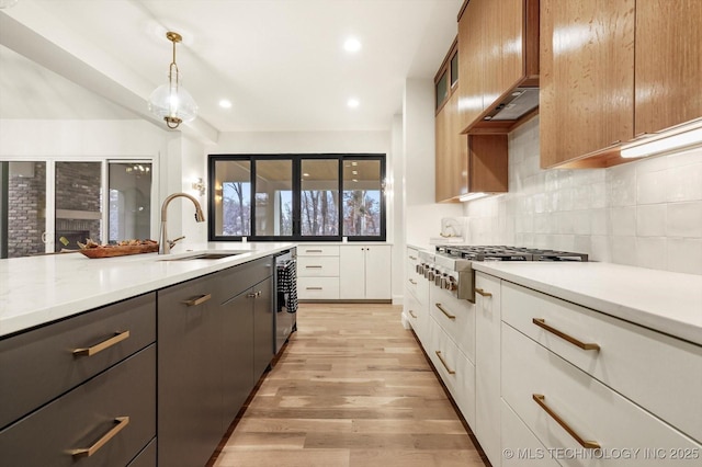 kitchen featuring decorative light fixtures, sink, backsplash, white cabinets, and stainless steel gas cooktop