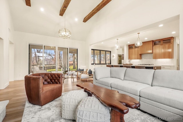 living room featuring beam ceiling, a wealth of natural light, and light wood-type flooring