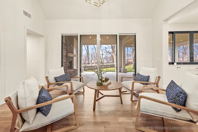 living area featuring lofted ceiling, a wealth of natural light, and light hardwood / wood-style floors