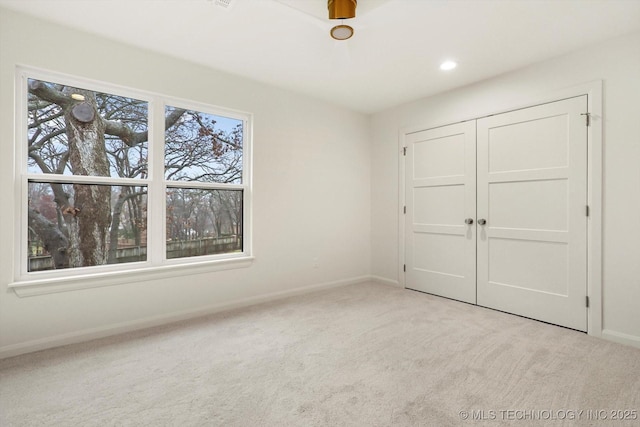 unfurnished bedroom featuring light colored carpet and a closet