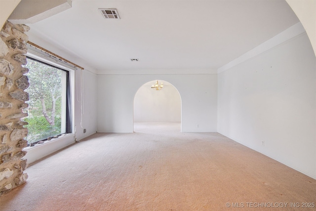 spare room featuring a chandelier and carpet floors