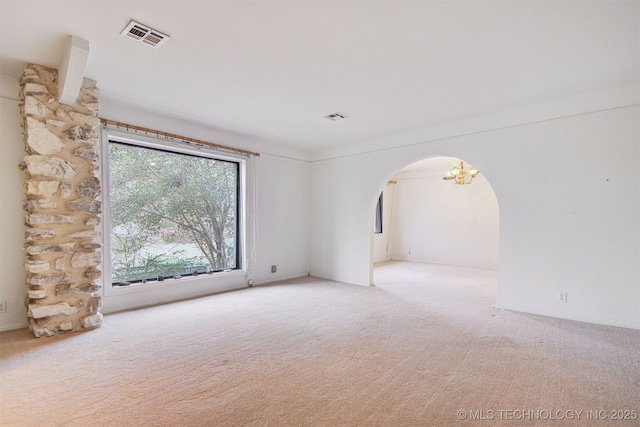 carpeted empty room featuring an inviting chandelier