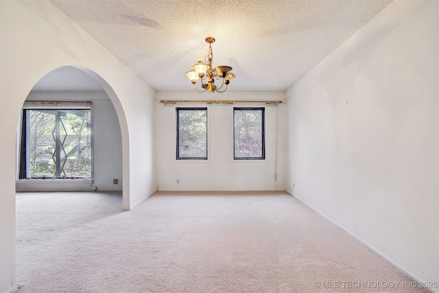 carpeted spare room featuring an inviting chandelier and a textured ceiling