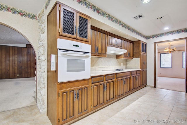 kitchen featuring white oven, light carpet, black electric cooktop, and decorative backsplash