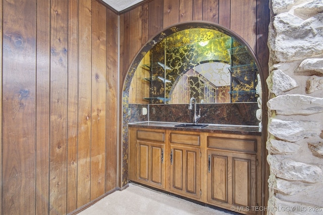 bar featuring sink and wood walls