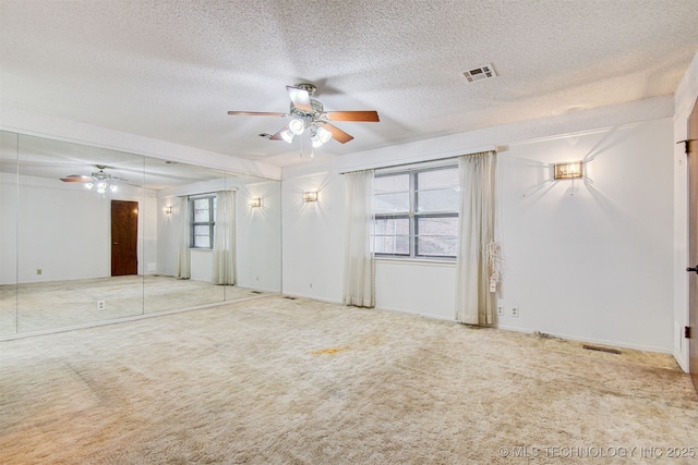 carpeted empty room featuring ceiling fan and a textured ceiling