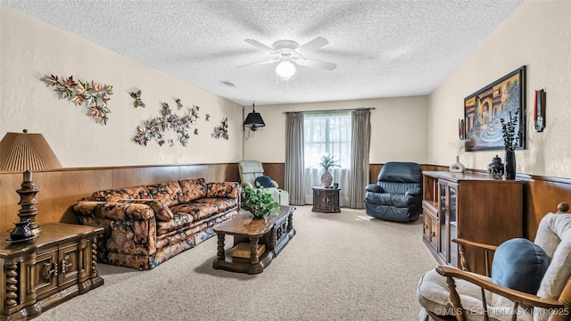 living room with ceiling fan, light colored carpet, a textured ceiling, and wood walls