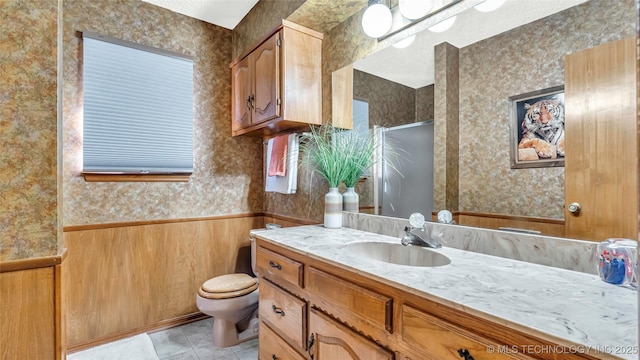 bathroom with wooden walls, tile patterned flooring, vanity, toilet, and a shower with door