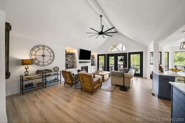 living room with lofted ceiling with beams, ceiling fan, light hardwood / wood-style floors, and french doors