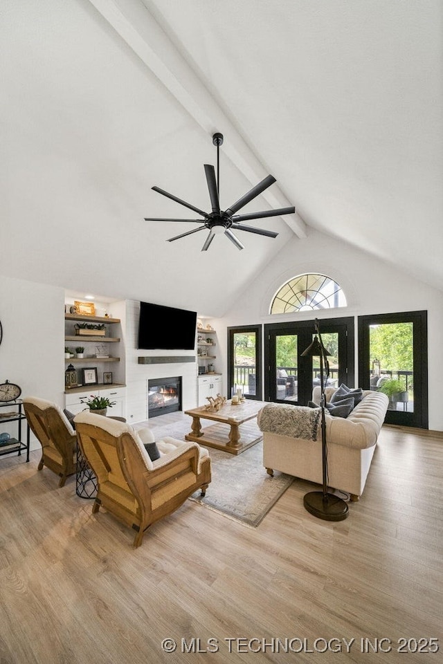 living room featuring high vaulted ceiling, a fireplace, ceiling fan, light hardwood / wood-style floors, and beam ceiling