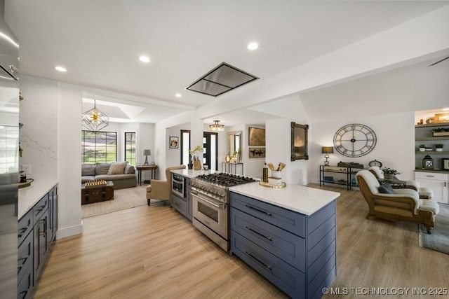 kitchen with decorative light fixtures, lofted ceiling with beams, high end stainless steel range oven, light stone counters, and light hardwood / wood-style flooring