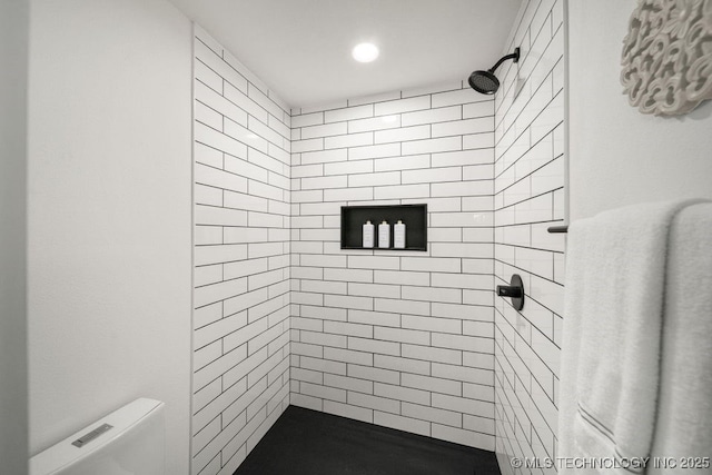 bathroom with a tile shower and toilet