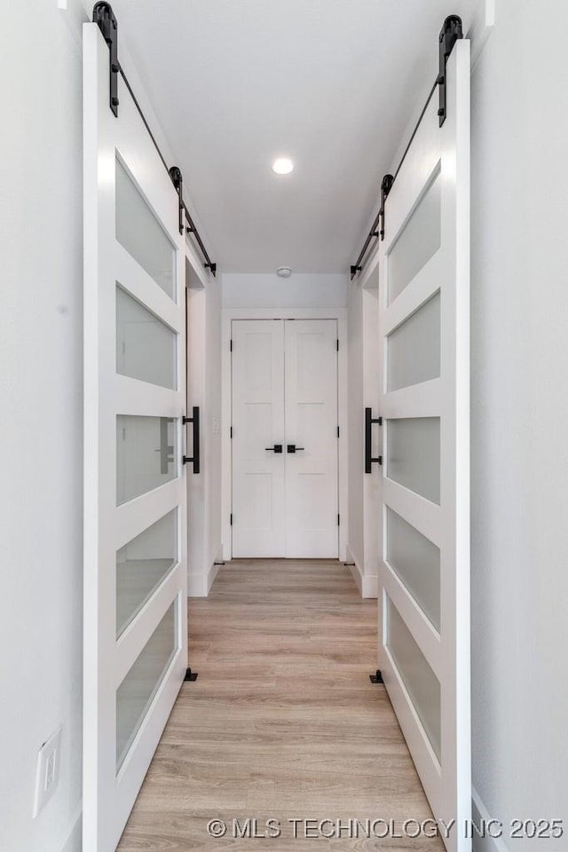 hallway with a barn door and light hardwood / wood-style flooring