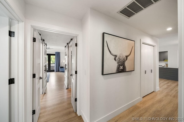 hallway with light hardwood / wood-style floors and a barn door