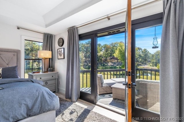 bedroom with a water view, access to exterior, and light hardwood / wood-style floors