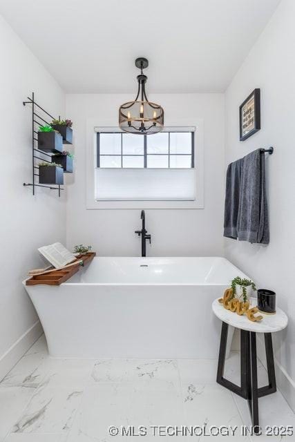 bathroom with an inviting chandelier and a tub