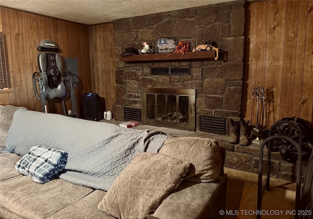living room featuring a stone fireplace, a textured ceiling, and wood walls