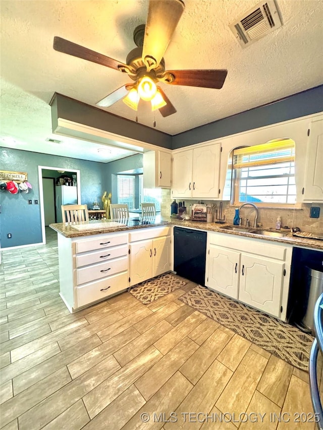 kitchen with white cabinetry, a textured ceiling, kitchen peninsula, and dishwasher