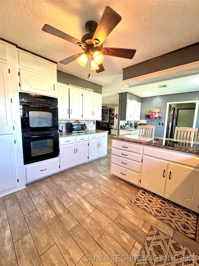 kitchen featuring backsplash, black appliances, light hardwood / wood-style floors, a textured ceiling, and white cabinets