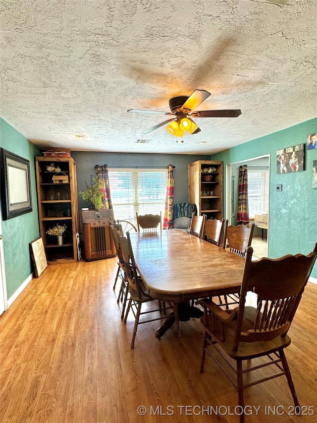 dining area featuring a textured ceiling, ceiling fan, and light wood-type flooring