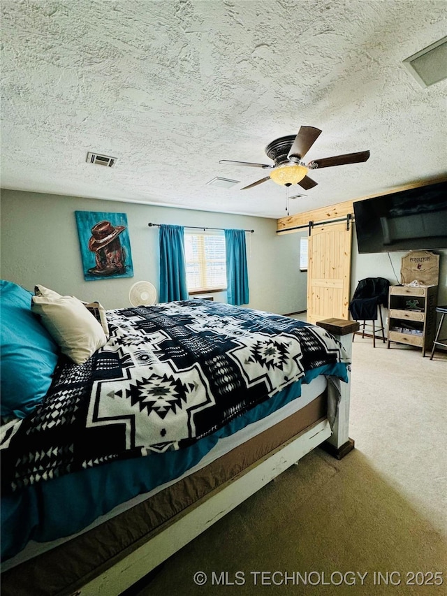 bedroom with a barn door, carpet flooring, a textured ceiling, and ceiling fan