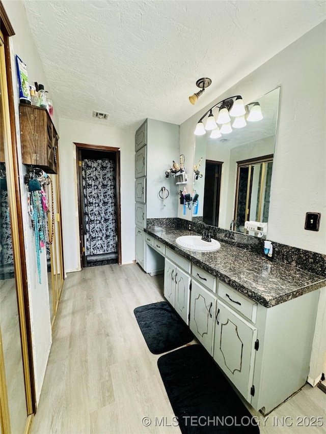 bathroom with hardwood / wood-style flooring, vanity, and a textured ceiling