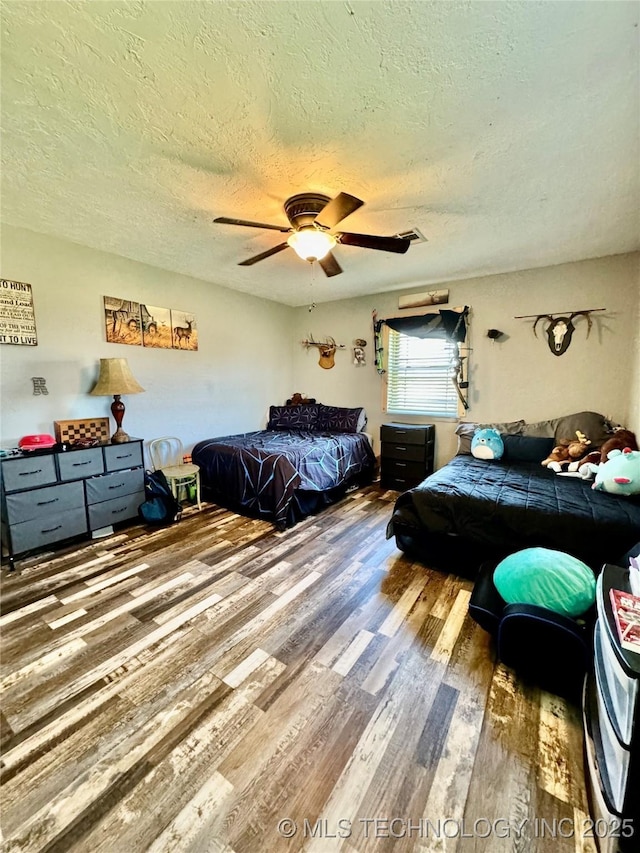 bedroom with hardwood / wood-style floors, a textured ceiling, and ceiling fan