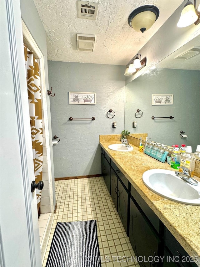 bathroom featuring tile patterned flooring, vanity, and a textured ceiling