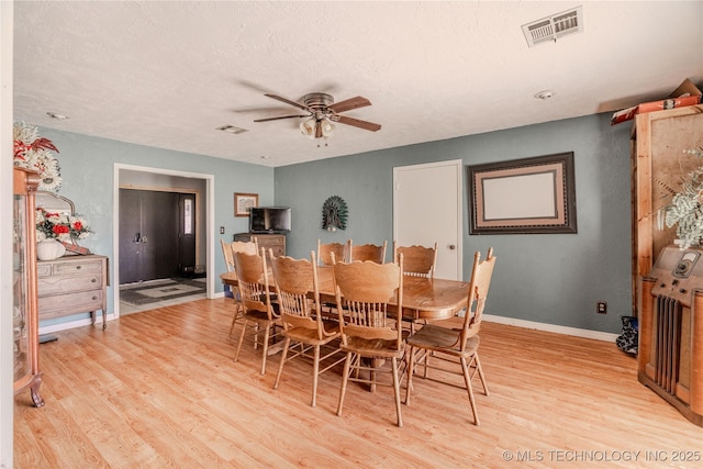 dining area featuring baseboards, visible vents, light wood finished floors, ceiling fan, and a textured ceiling