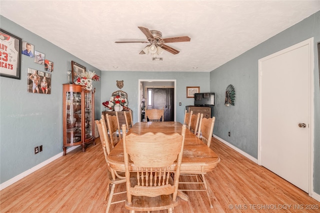 dining space with baseboards, light wood-type flooring, and ceiling fan