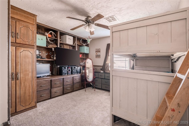 bedroom featuring visible vents, light colored carpet, a textured ceiling, and ceiling fan