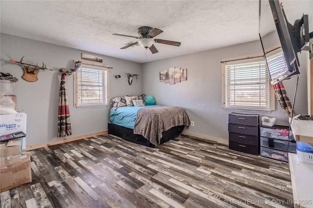 bedroom with wood finished floors, baseboards, and a textured ceiling