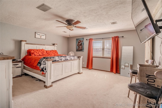 bedroom with light carpet, visible vents, a textured ceiling, and ceiling fan