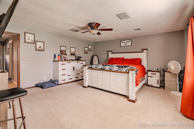 bedroom featuring ceiling fan, light colored carpet, visible vents, and a textured ceiling