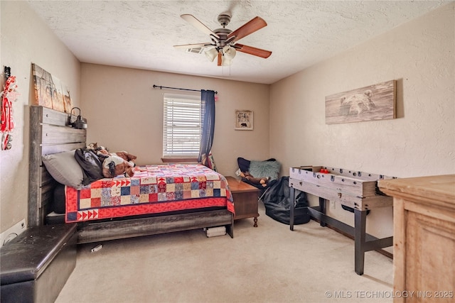 carpeted bedroom with ceiling fan, a textured wall, visible vents, and a textured ceiling