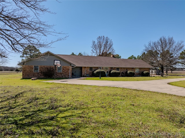 single story home with brick siding, a chimney, concrete driveway, and a front yard