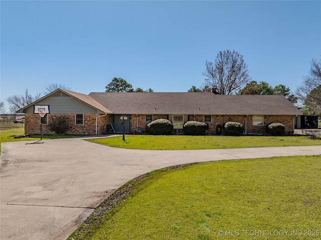 ranch-style home with driveway, brick siding, and a front lawn